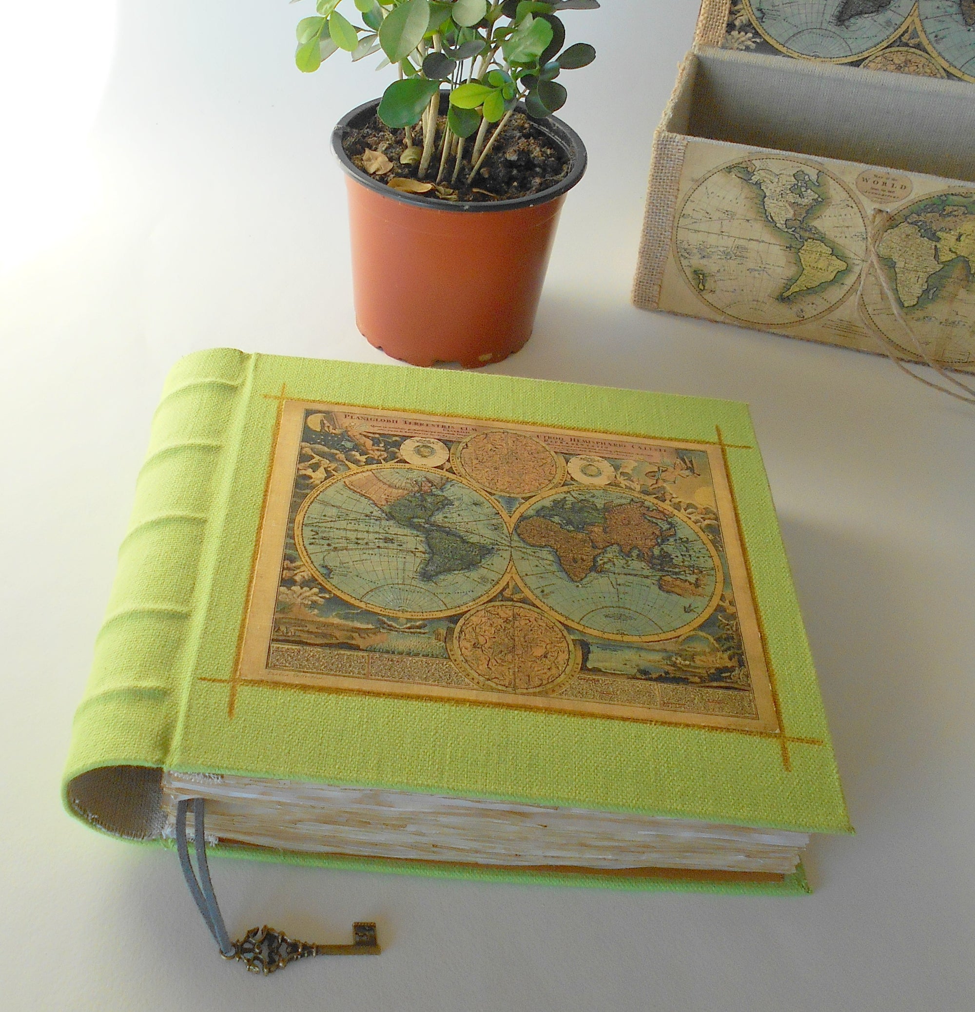 
          
            A handmade green fabric hardcover journal with a brown vintage world map on the cover and a curved spine and a bookmark
          
        