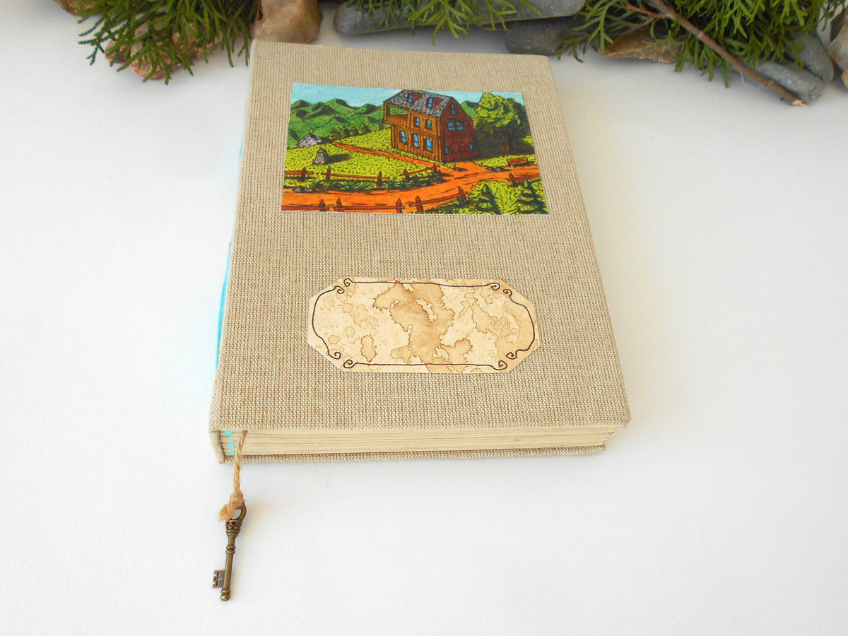 This is a handmade journal with linen fabric hardcovers and a fineÉaster Island heads art print on the front and also an empty coffee-stained title label so you can write your title on it. The art is from my art collection and is titled &#39;Gather Inn?&#39;. This journal is an inspirational book for you to use on the travel, for your daily diary journaling, or also for your planning and sketching of new projects and new poetry or novels.