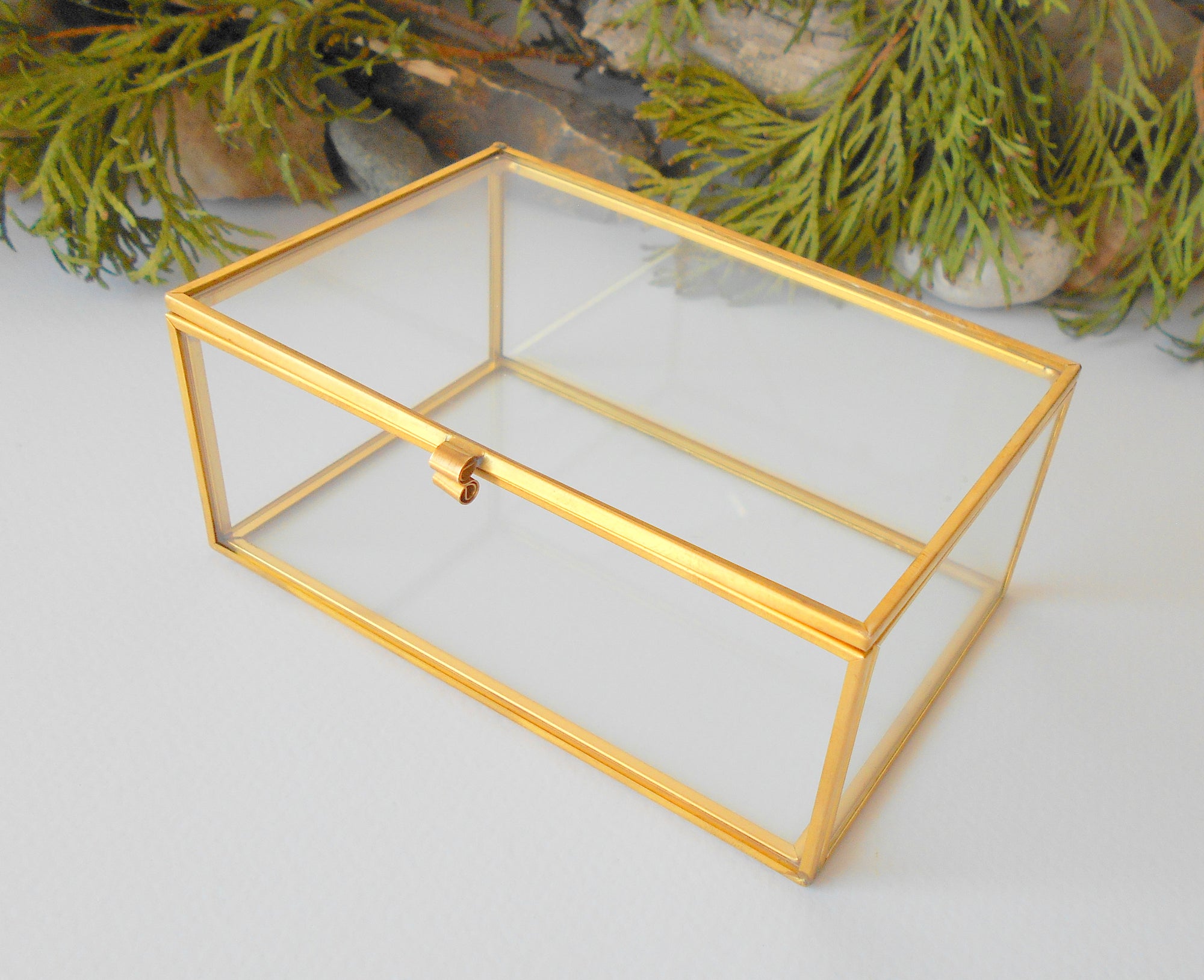 This is a small glass box made of real glass and metal edges and metal hinges that closes with a gold-color closing that may display various things like jewelry, miniatures, crystals, or other small objects of importance to you or your friends. It can be used for tiny or small terrarium projects. The edges of the box are also gold-color metal pieces.&nbsp;