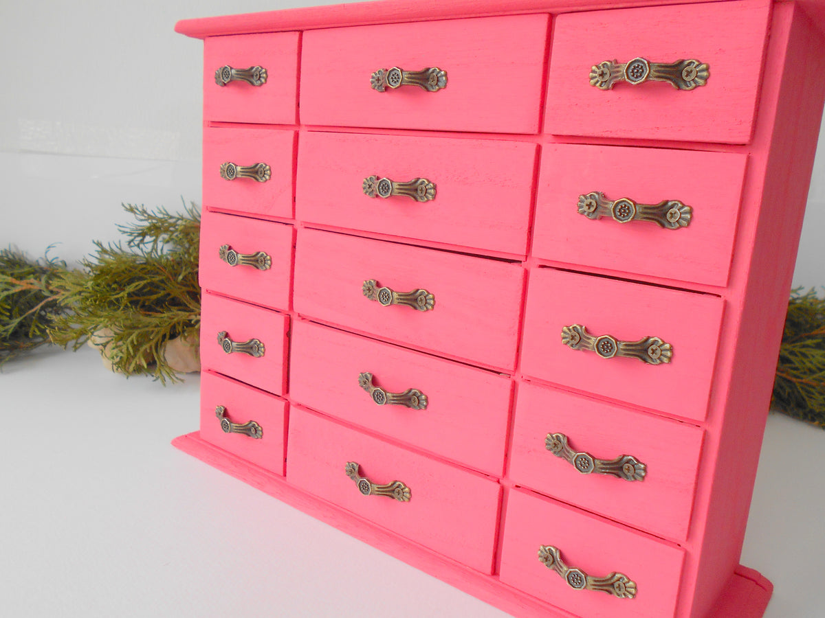 This wooden box with 15 drawers is made of bamboo wood and has metal pulls with a vintage bronze color. The surface of the box is smooth and it has 15 drawers in two different sizes- 5 bigger and 10 smaller. The color of the box is dark pink which I created from 2 parts Crimson Red and one part of Opaque White acrylic paints.