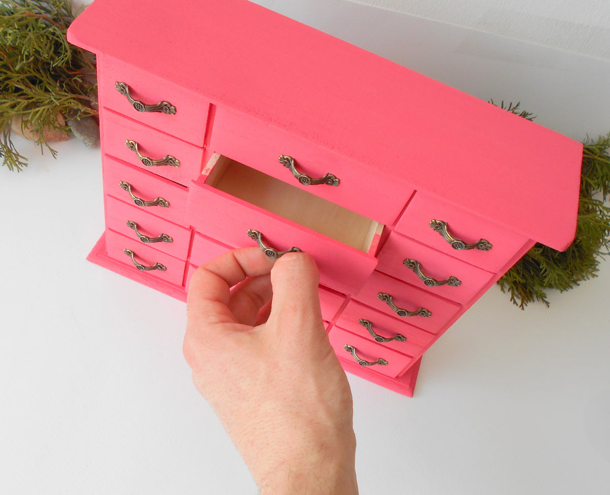 This wooden box with 15 drawers is made of bamboo wood and has metal pulls with a vintage bronze color. The surface of the box is smooth and it has 15 drawers in two different sizes- 5 bigger and 10 smaller. The color of the box is dark pink which I created from 2 parts Crimson Red and one part of Opaque White acrylic paints.