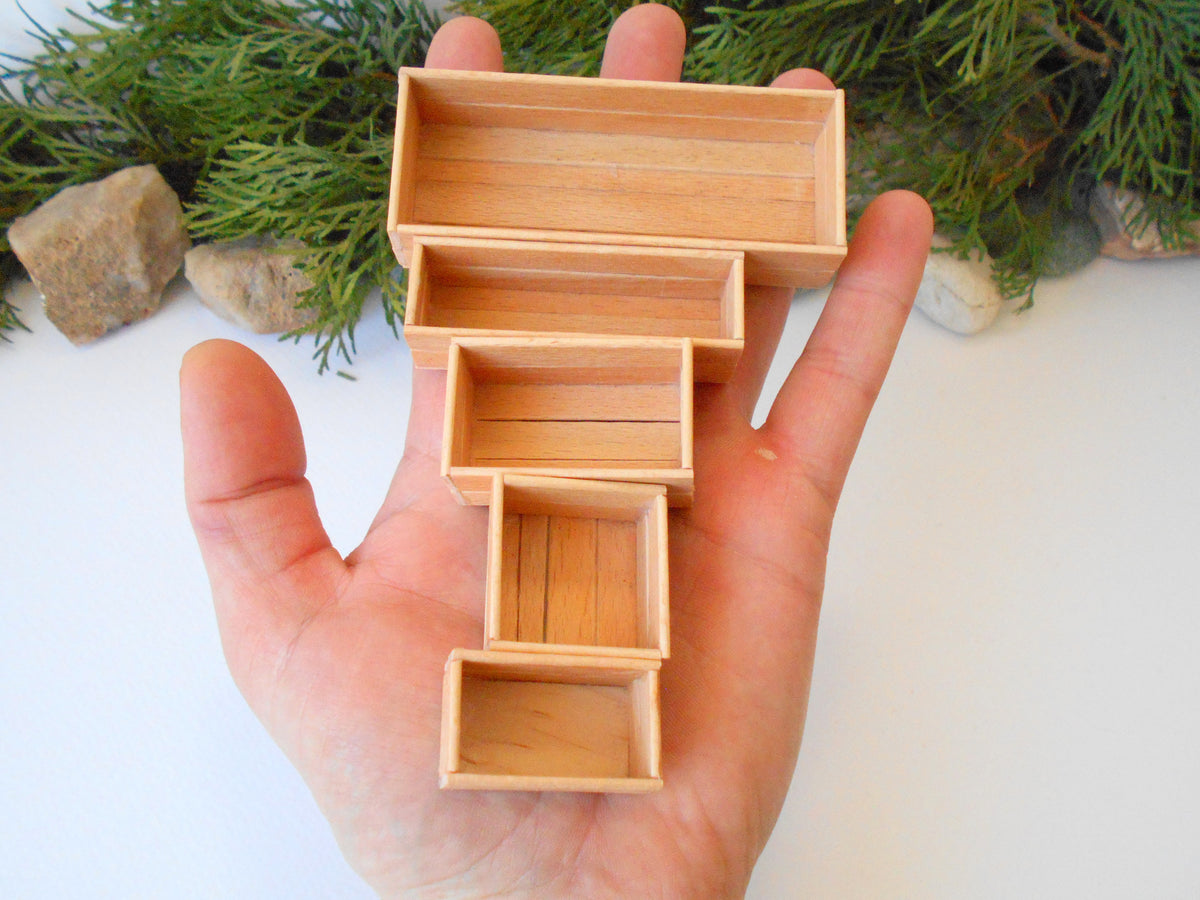 This is a set of 5 miniature boxes that are in 1/12 in scale. I craft them on order from beech popsicle sticks that I saved from being thrown away when I worked in an Ice cream factory in the Netherlands in 2023. The set consists of 5 different boxes.