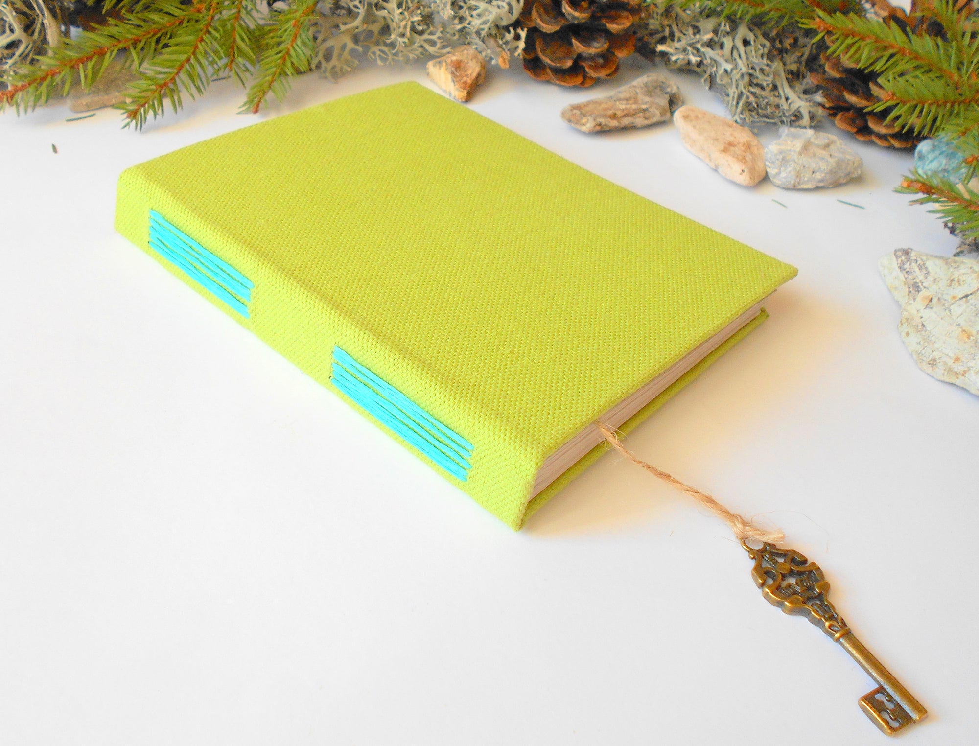 Handmade green linen fabric eco-friendly journal with hardcovers and 100% recycled pages with a bookmark accessory from a twine cord and a vintage key on the end.