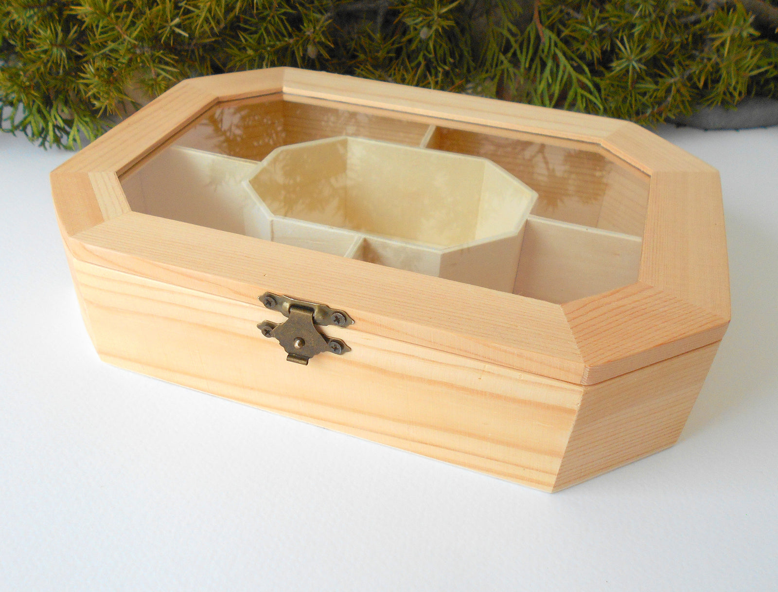 This is a wooden box with a glass display that is made of bamboo wood and that has metal hinges and closes with a bronze-color closing that may display various things like jewelry, miniatures, crystals, or other small objects of importance to you or your friends.