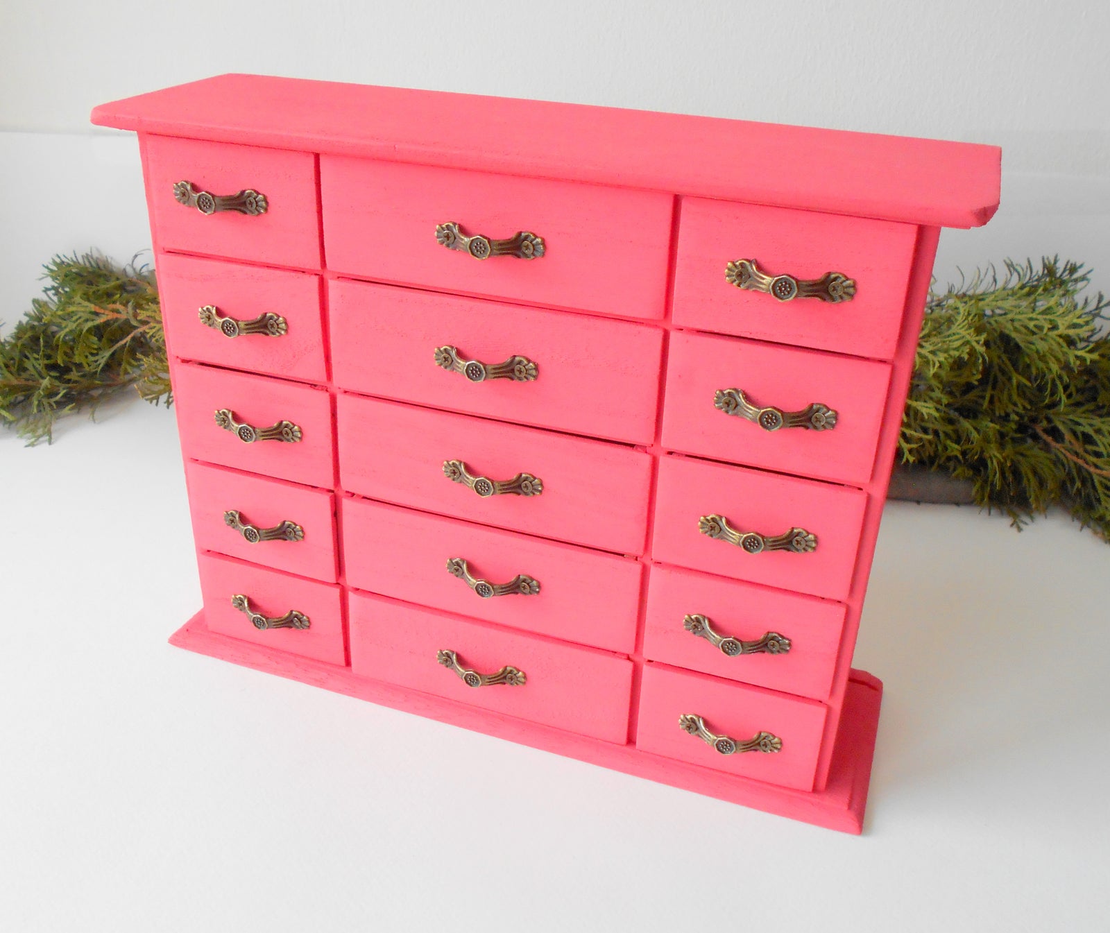 This wooden box with 15 drawers is made of bamboo wood and has metal pulls with a vintage bronze color. The surface of the box is smooth and it has 15 drawers in two different sizes- 5 bigger and 10 smaller. The color of the box is dark pink which I created from 2 parts Crimson Red and one part of Opaque White acrylic paints.