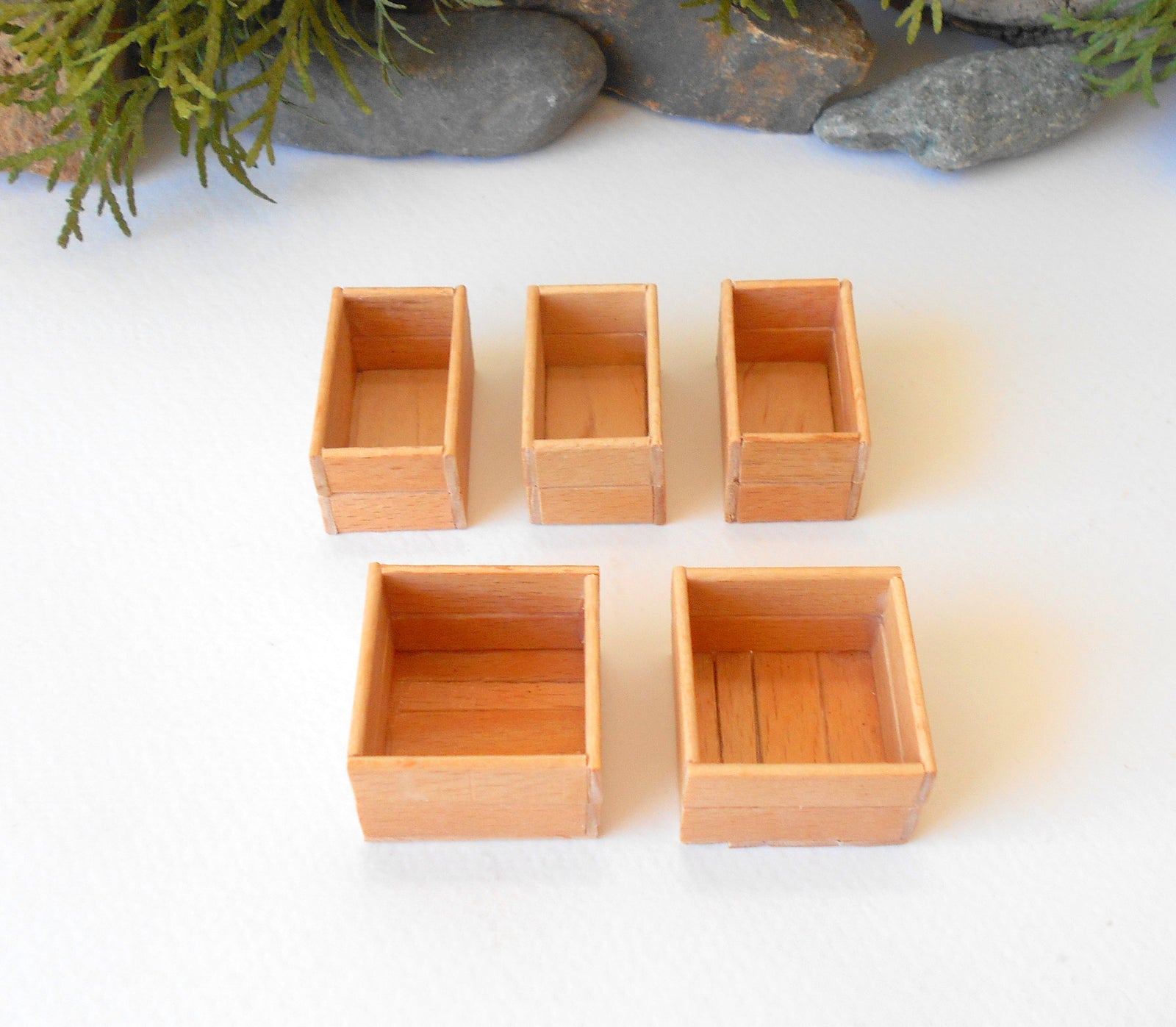 This is a set of 5 miniature boxes that are in 1/12 in scale. I craft them on order from beech popsicle sticks that I saved from being thrown away when I worked in an Ice cream factory in the Netherlands in 2023. The set consists of 2 bigger square boxes and 3 smaller rectangular boxes. 