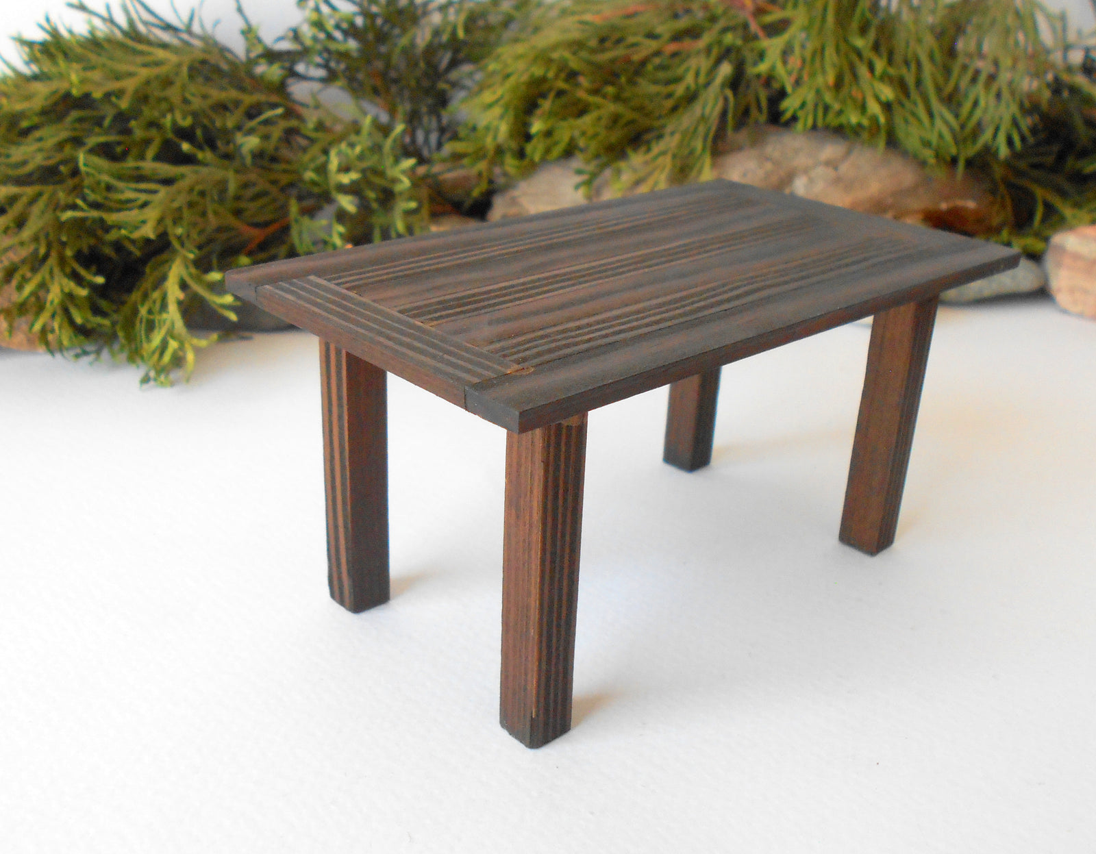 This is a handmade miniature dining or kitchen table on a&nbsp;1/12th scale that is suitable for 6 mini chairs on a 1/12th scale. I handmade this table on order with real pine wood boards and beams and with water-based eco-friendly glue. I have stained that table with Italian eco-friendly mordant in dark brown.