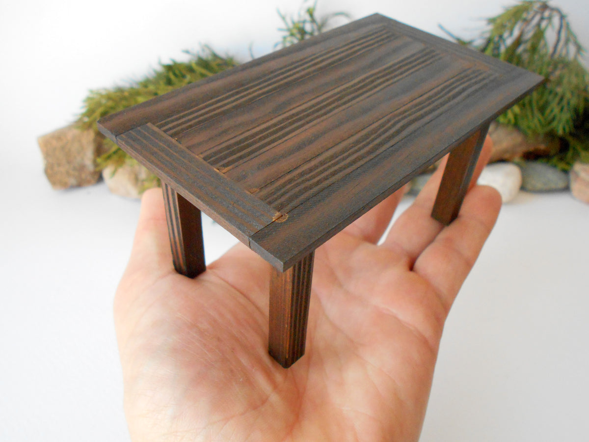 This is a handmade miniature dining or kitchen table on a&amp;nbsp;1/12th scale that is suitable for 6 mini chairs on a 1/12th scale. I handmade this table on order with real pine wood boards and beams and with water-based eco-friendly glue. I have stained that table with Italian eco-friendly mordant in dark brown.