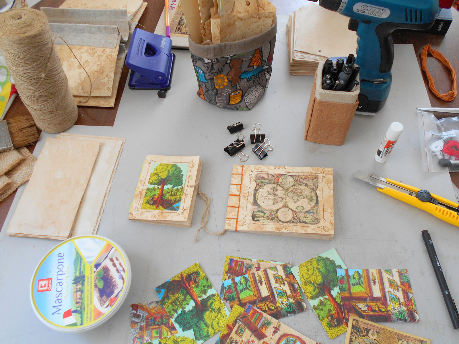 Handmade crafts, journals, art prints, instruments and twine cord on a workshop desk table of a handmade craftsman