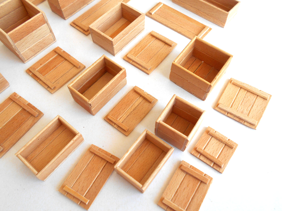 A collection of miniature wooden crates and boxes in various sizes, arranged on a plain white background.