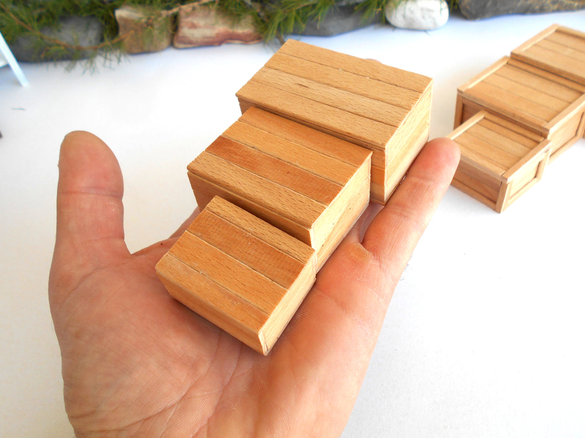 A hand holding a small wooden block puzzle with three sliding steps, with additional matching wooden blocks visible in the background on a white surface.