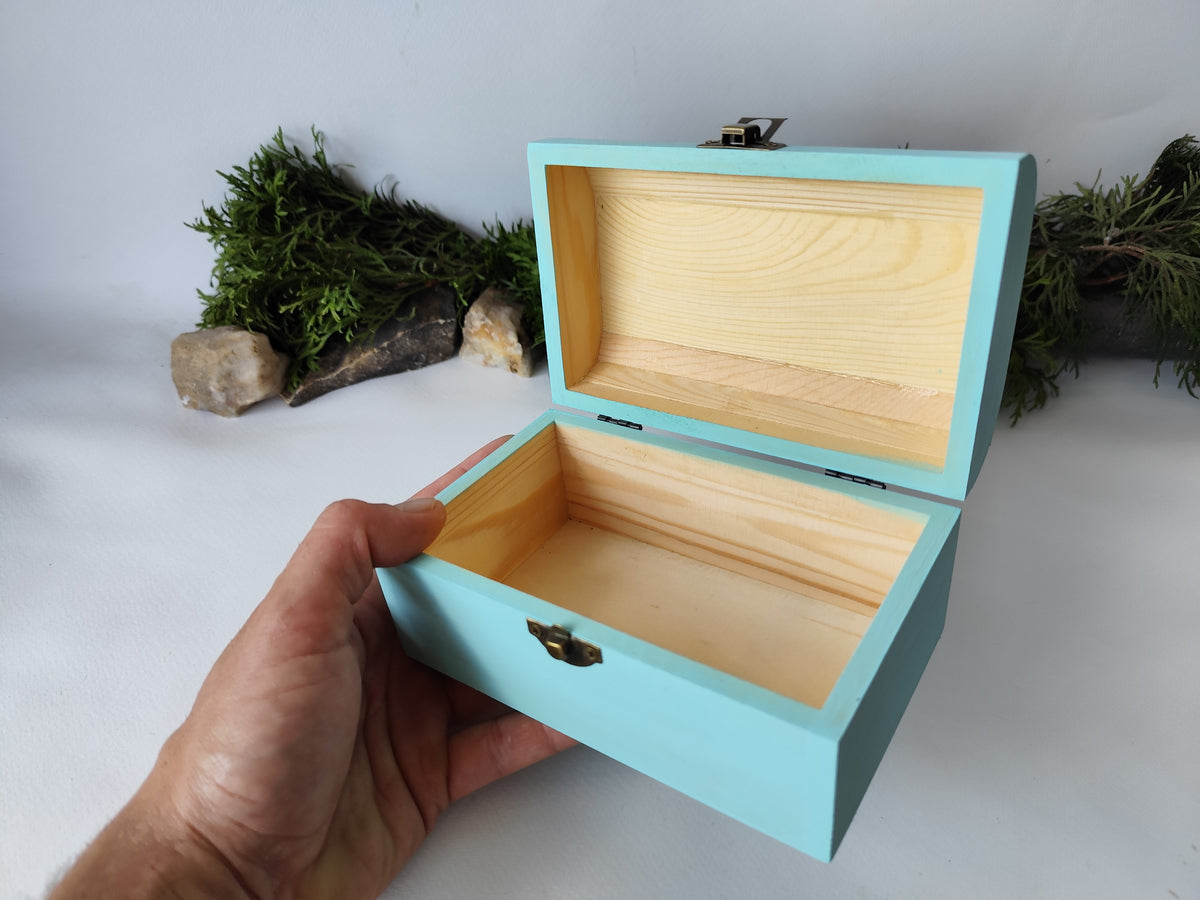 This mint painted chest wooden box is made of quality pine wood and has metal hinges with bronze-color and the cap and the body of the box have bronze-color closing. The cap of the small box is curved like in a chest box. The thickness of the box walls is 0.3 inches which makes the box strong and lasting. I have refined and sanded the box to have smooth surface and I have colored it with a mint light blue color that I developed myself with white, blue,  and green acrylic paints.