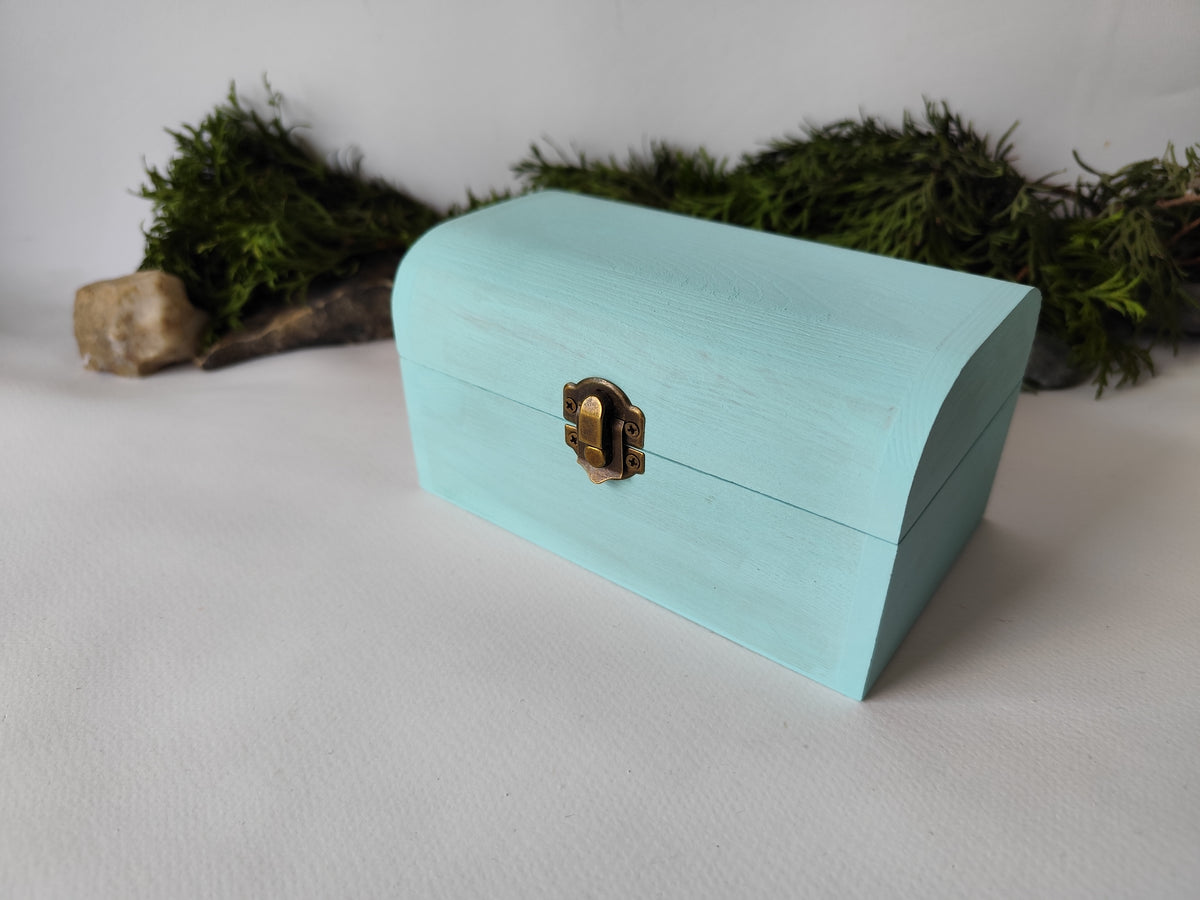 This mint painted chest wooden box is made of quality pine wood and has metal hinges with bronze-color and the cap and the body of the box have bronze-color closing. The cap of the small box is curved like in a chest box. The thickness of the box walls is 0.3 inches which makes the box strong and lasting. I have refined and sanded the box to have smooth surface and I have colored it with a mint light blue color that I developed myself with white, blue,  and green acrylic paints.