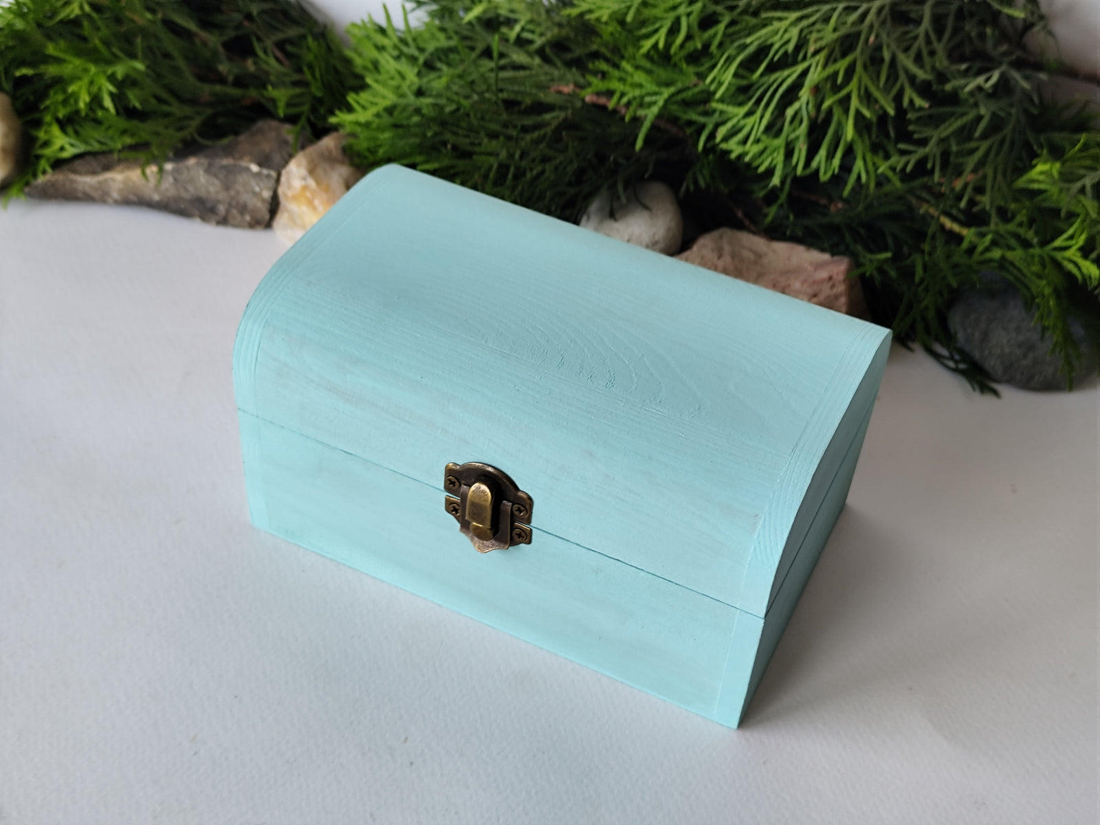 This mint painted chest wooden box is made of quality pine wood and has metal hinges with bronze-color and the cap and the body of the box have bronze-color closing. The cap of the small box is curved like in a chest box. The thickness of the box walls is 0.3 inches which makes the box strong and lasting. I have refined and sanded the box to have smooth surface and I have colored it with a mint light blue color that I developed myself with white, blue,  and green acrylic paints.
